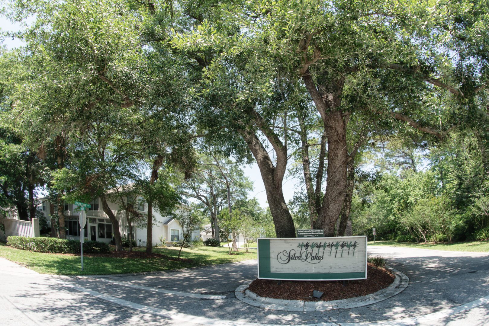 A sign in front of some trees and buildings